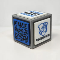 3D printed cube with one side featuring a QR code and the other featuring logos and slogans.