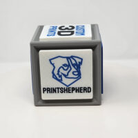 3D printed cube with one side featuring a QR code and the other featuring logos and slogans.