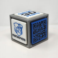 3D printed cube with one side featuring a QR code and the other featuring logos and slogans.