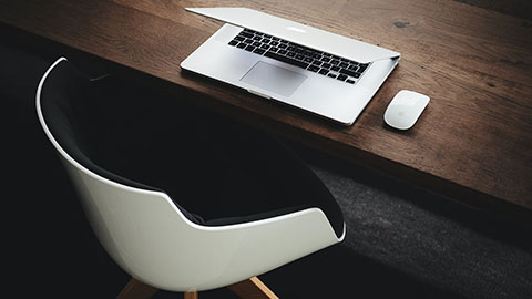 A closed laptop in front of an empty chair.